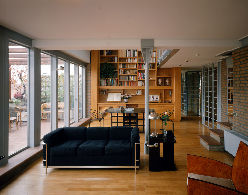 Immagine di un soggiorno design di medie dimensioni e stile loft con libreria, pareti bianche, parquet chiaro, camino classico, cornice del camino in mattoni e pavimento marrone