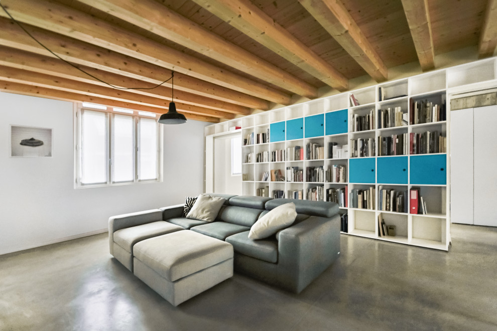 Cette photo montre une salle de séjour tendance de taille moyenne et ouverte avec une bibliothèque ou un coin lecture, un mur blanc, sol en béton ciré et un sol gris.