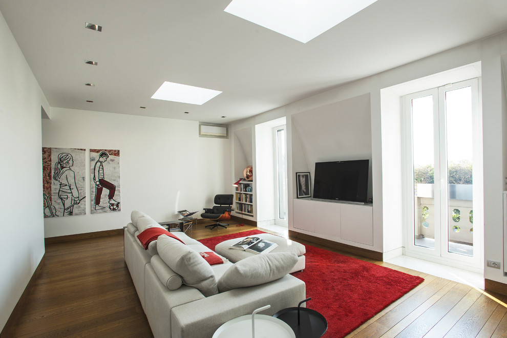 Exempel på ett stort modernt allrum med öppen planlösning, med vita väggar, mellanmörkt trägolv och en fristående TV