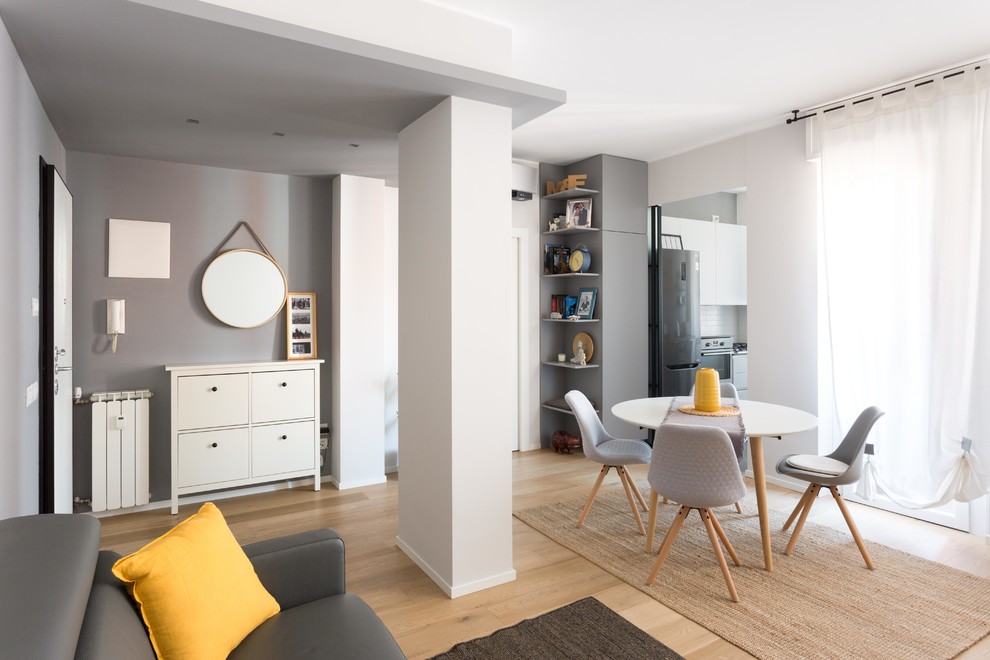 Immagine di un soggiorno minimal di medie dimensioni e aperto con libreria, pareti grigie e parquet chiaro