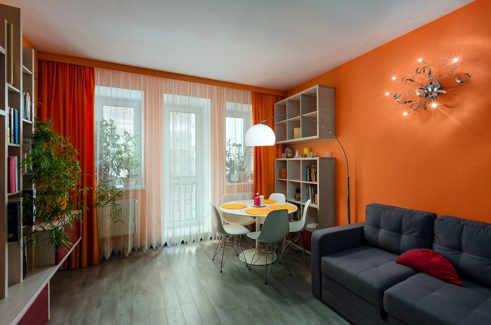 Idéer för ett mellanstort modernt allrum med öppen planlösning, med ett bibliotek, orange väggar, laminatgolv och en väggmonterad TV