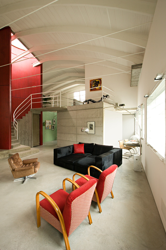 Exemple d'une salle de séjour industrielle avec sol en béton ciré et canapé noir.