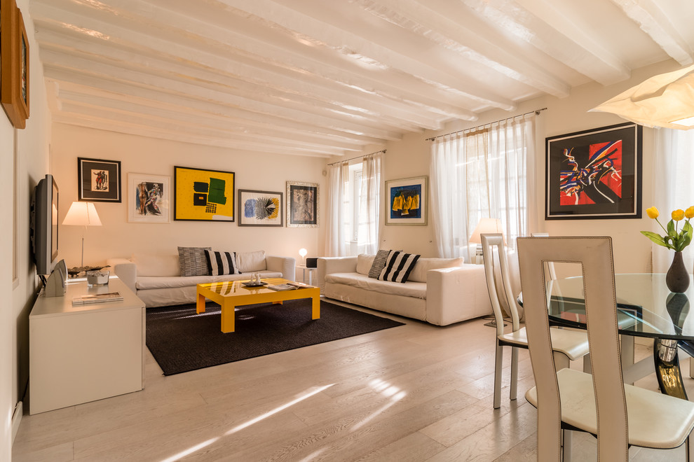 Esempio di un soggiorno design aperto con parquet chiaro, TV a parete, pareti bianche, nessun camino e pavimento beige