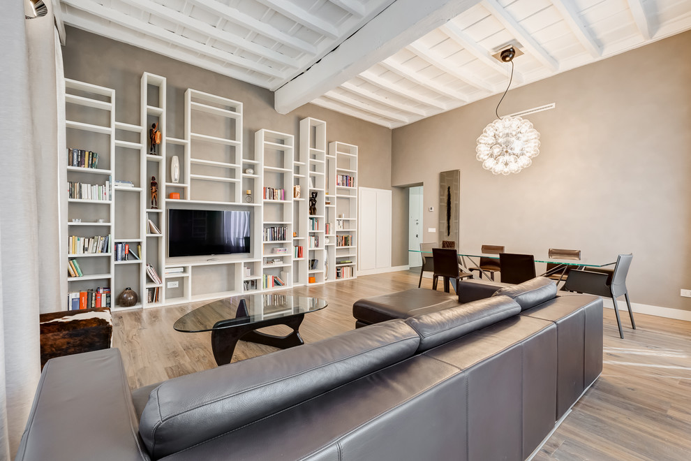 Esempio di un grande soggiorno minimal aperto con pareti beige, parquet chiaro, TV a parete, libreria, nessun camino e pavimento marrone