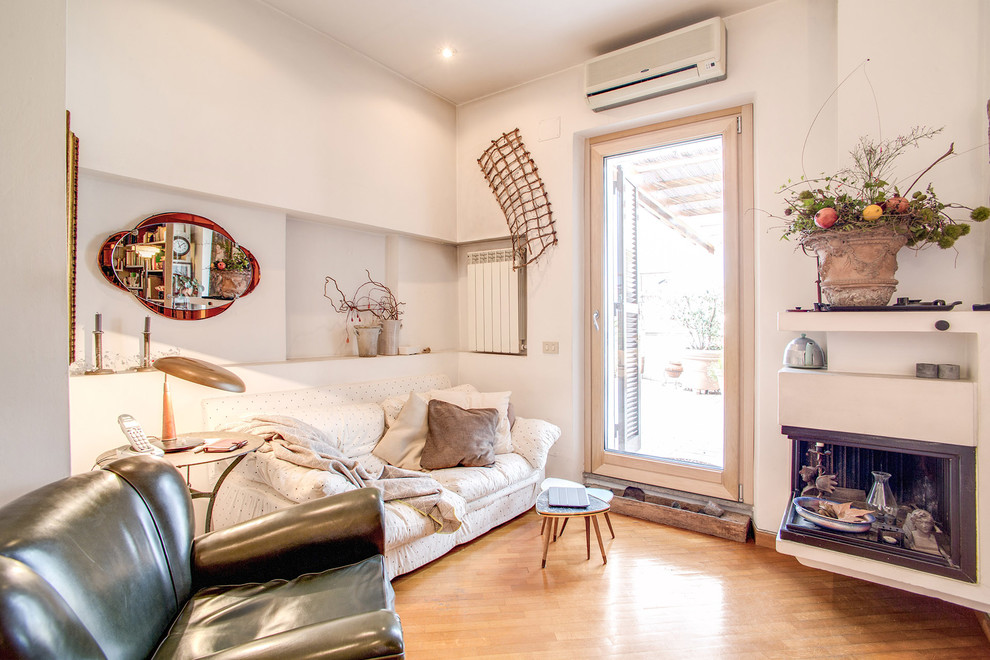 Ejemplo de sala de estar abierta bohemia pequeña con paredes blancas, suelo de madera clara, chimenea de esquina, marco de chimenea de yeso y suelo beige