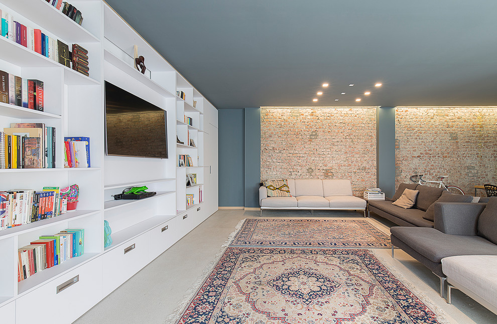 Foto de salón con barra de bar abierto actual grande con paredes multicolor, suelo de cemento, televisor colgado en la pared y suelo gris