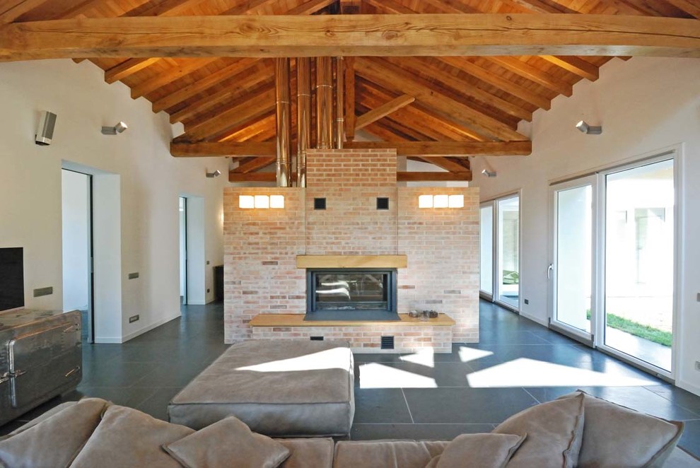 This is an example of a country living room in Other with a two-sided fireplace, a brick fireplace surround and white walls.
