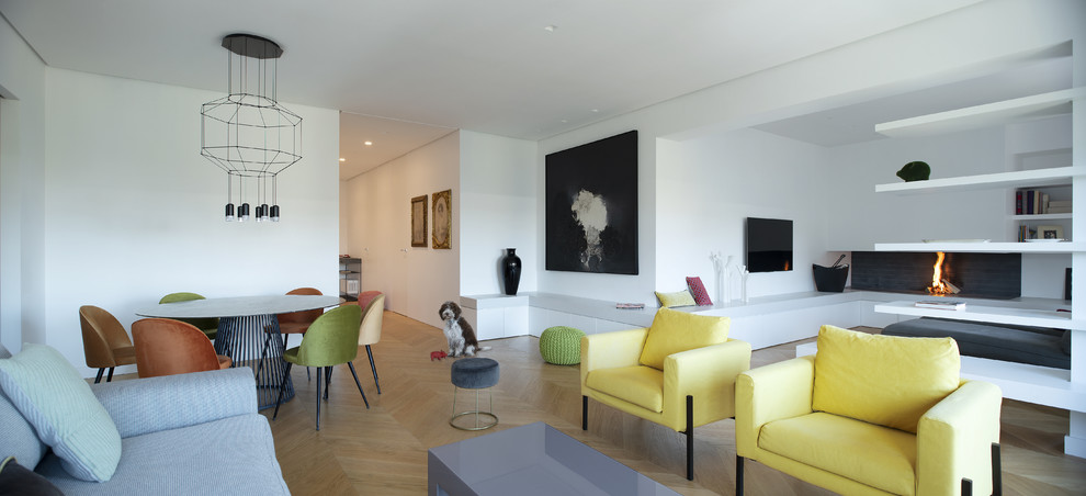 Immagine di un soggiorno design con pareti bianche, parquet chiaro, camino sospeso e TV a parete
