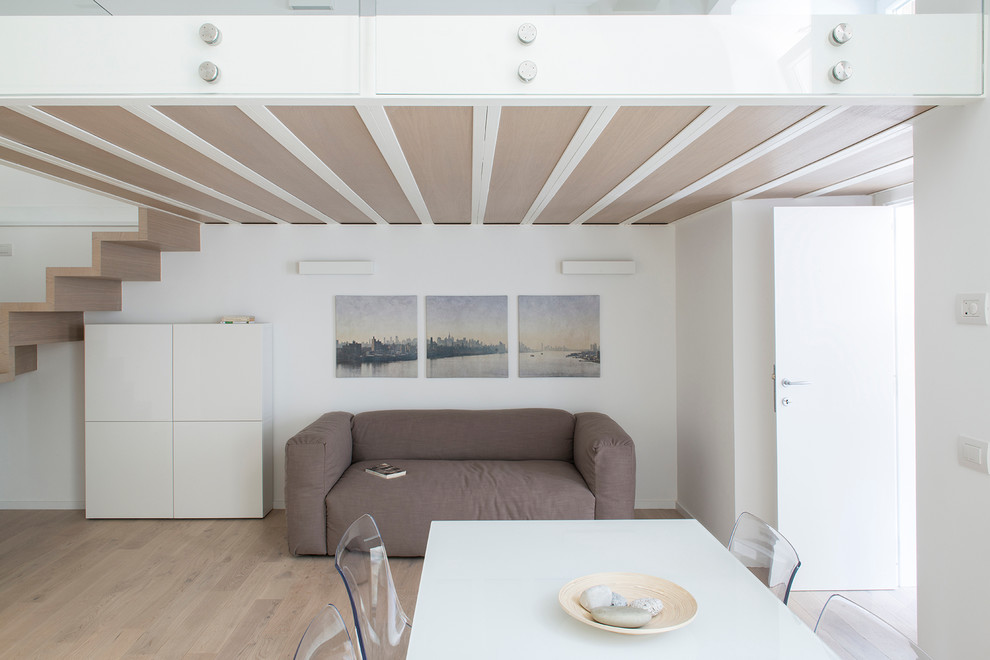 Modelo de salón con barra de bar tipo loft contemporáneo de tamaño medio sin chimenea con paredes blancas, suelo de madera clara y pared multimedia