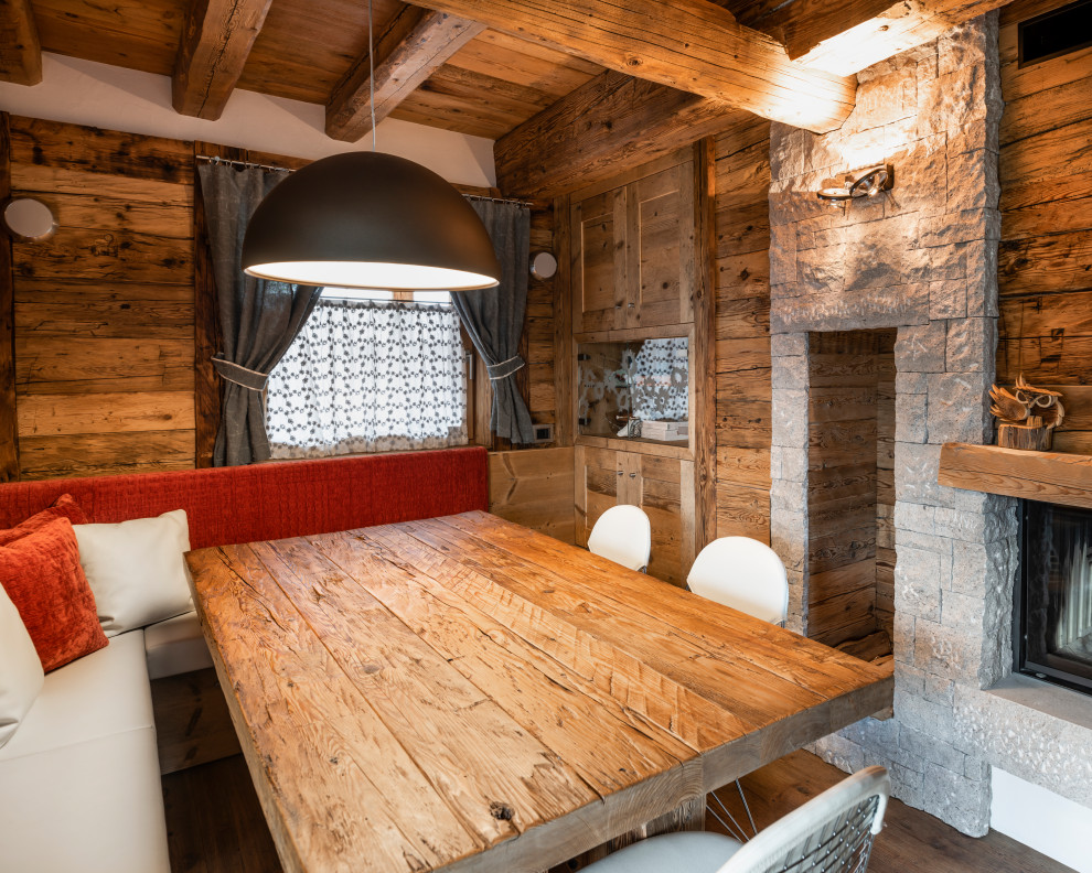 Kleines Rustikales Esszimmer mit weißer Wandfarbe, braunem Holzboden, Kamin und Kaminumrandung aus Holz