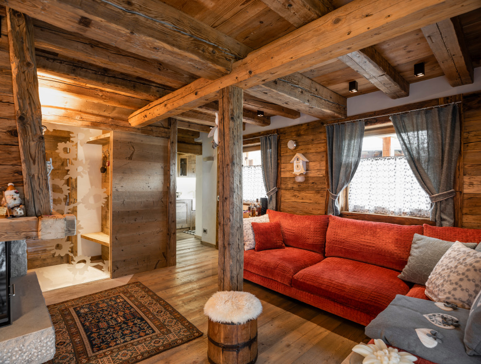 Imagen de salón abierto rural pequeño con paredes blancas, suelo de madera en tonos medios, todas las chimeneas, marco de chimenea de madera y televisor colgado en la pared