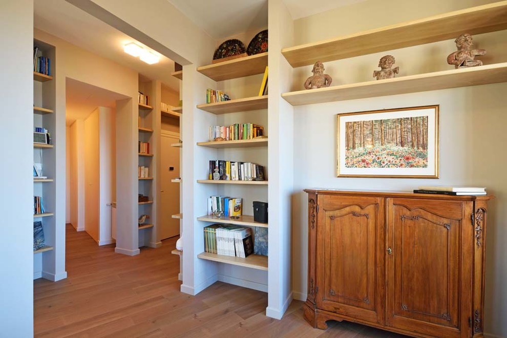 Пример оригинального дизайна: открытая гостиная комната в стиле модернизм с с книжными шкафами и полками, желтыми стенами, полом из ламината и отдельно стоящим телевизором без камина