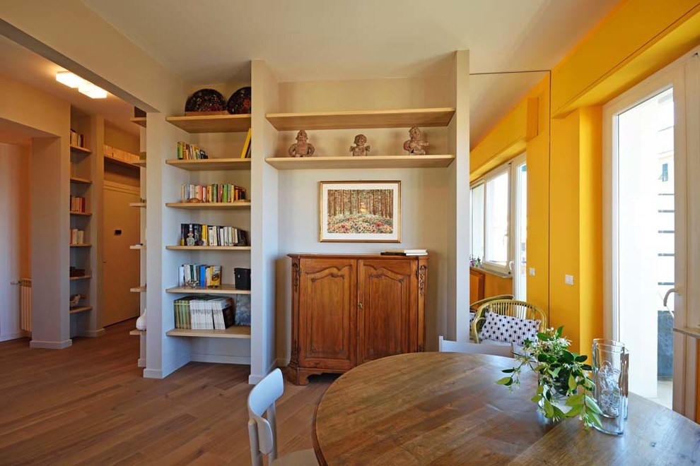 Ispirazione per un soggiorno minimalista aperto con libreria, pareti gialle, pavimento in laminato, nessun camino e TV autoportante