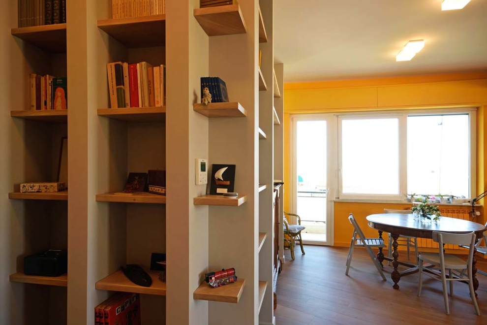 Esempio di un soggiorno moderno aperto con libreria, pareti gialle, pavimento in laminato, nessun camino e TV autoportante