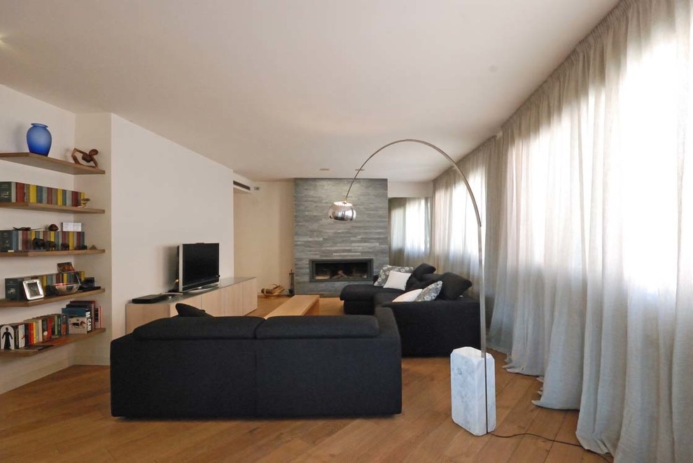 Cette photo montre un salon moderne ouvert avec un mur blanc, un sol en bois brun, une cheminée ribbon et un manteau de cheminée en pierre.