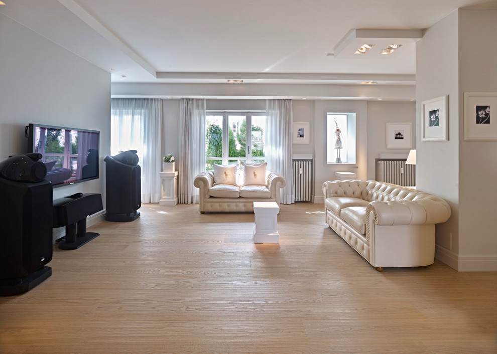 Diseño de sala de estar abierta clásica extra grande con suelo de madera clara y televisor colgado en la pared