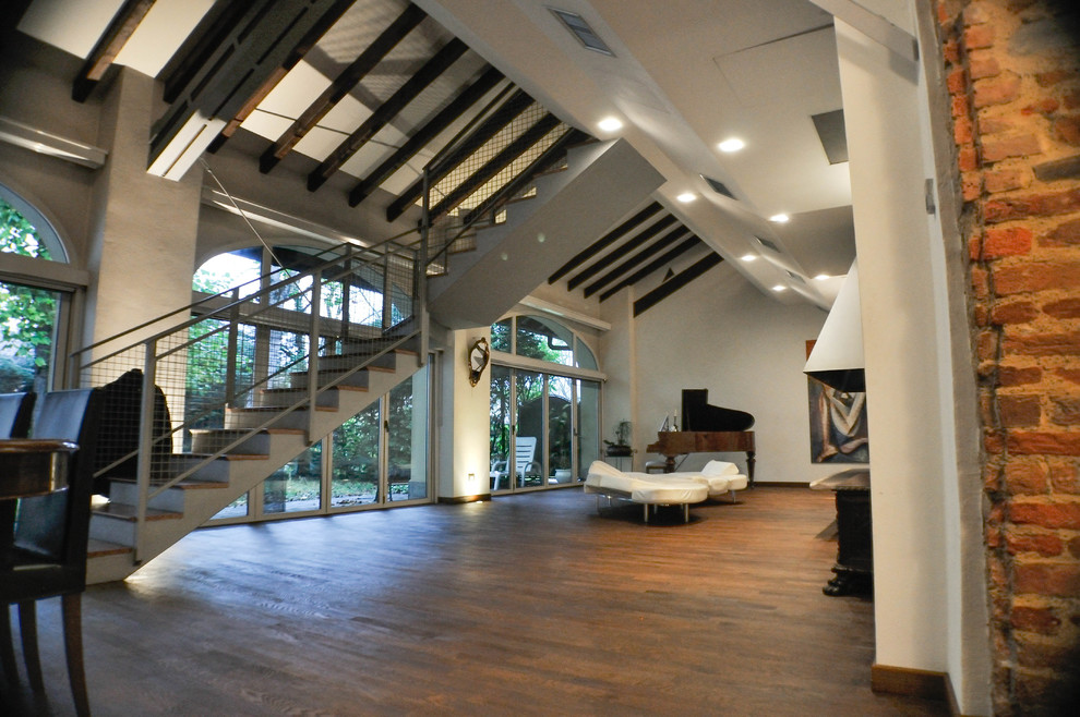 Foto di un ampio soggiorno moderno aperto con parquet scuro, camino bifacciale, cornice del camino in metallo, TV a parete, pavimento marrone e sala formale