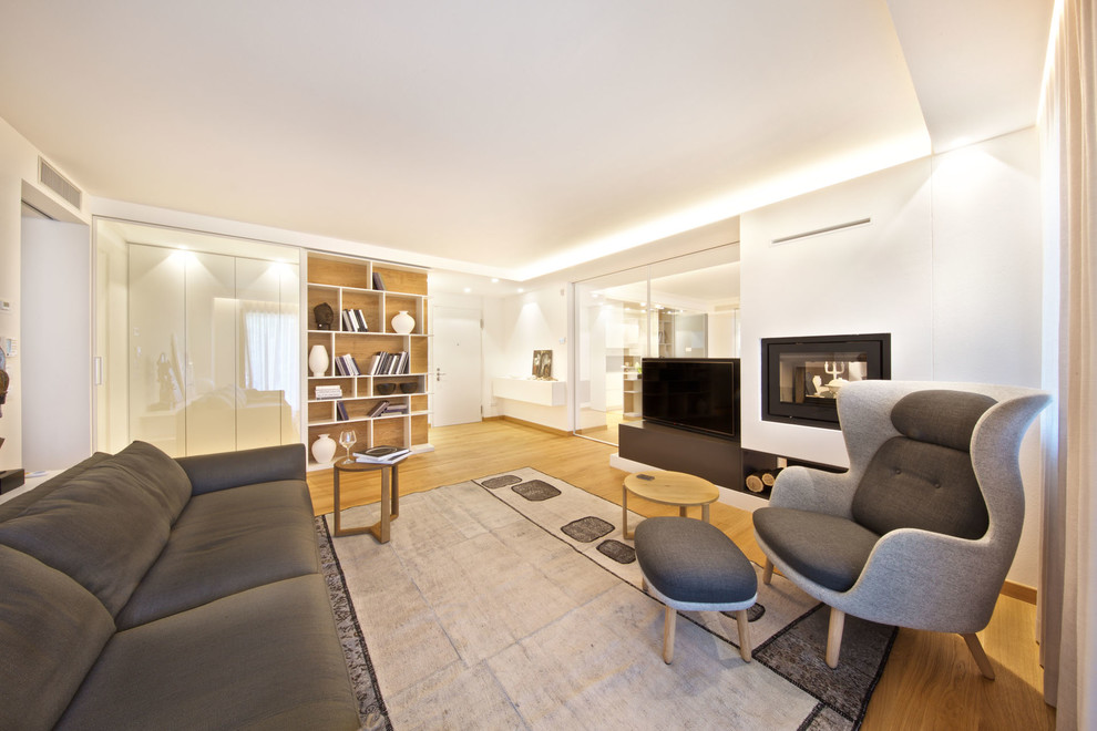 Imagen de salón abierto actual grande con paredes blancas, suelo de madera en tonos medios, chimenea lineal, marco de chimenea de yeso y televisor independiente