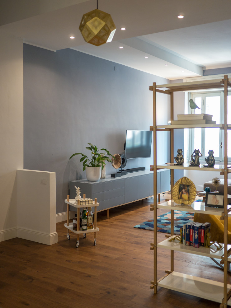 Immagine di un soggiorno contemporaneo di medie dimensioni e aperto con libreria, pareti blu, pavimento in legno massello medio, TV a parete e pavimento marrone