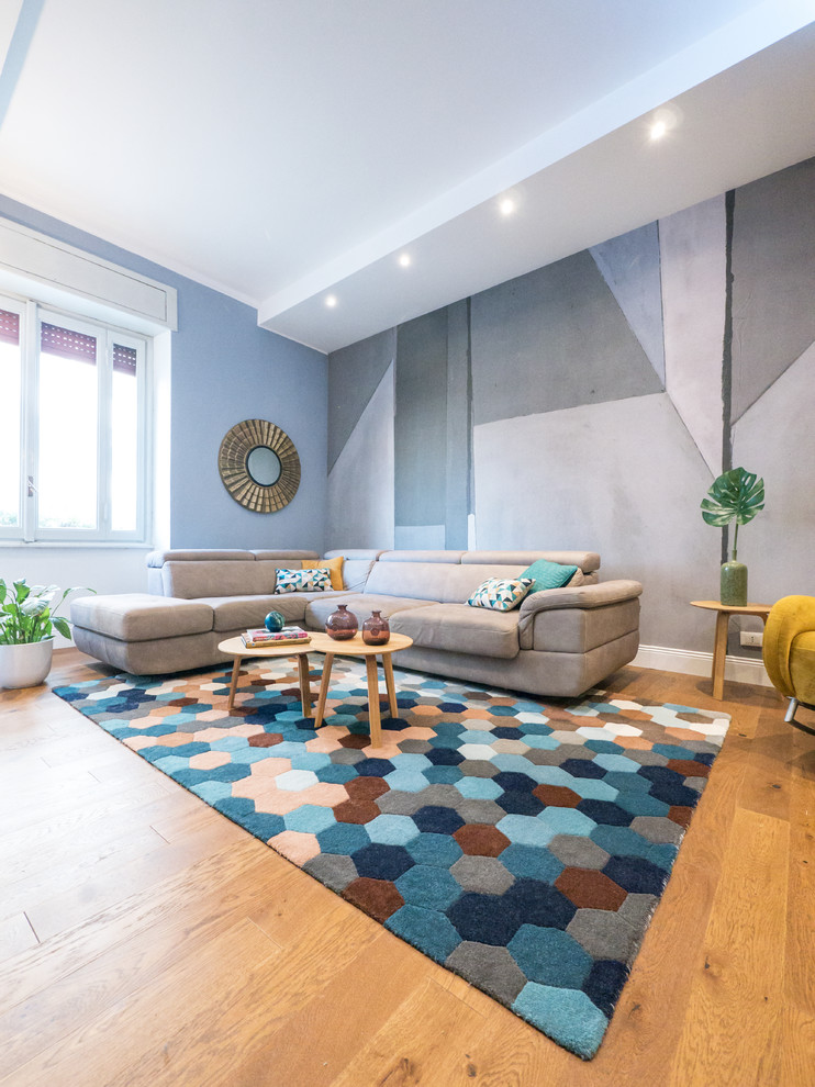 Ejemplo de salón contemporáneo con paredes azules, suelo de madera en tonos medios, televisor colgado en la pared y suelo marrón