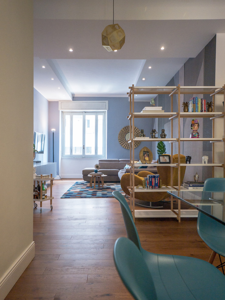 Idee per un soggiorno minimal di medie dimensioni e aperto con libreria, pareti blu, pavimento in legno massello medio, TV a parete e pavimento marrone