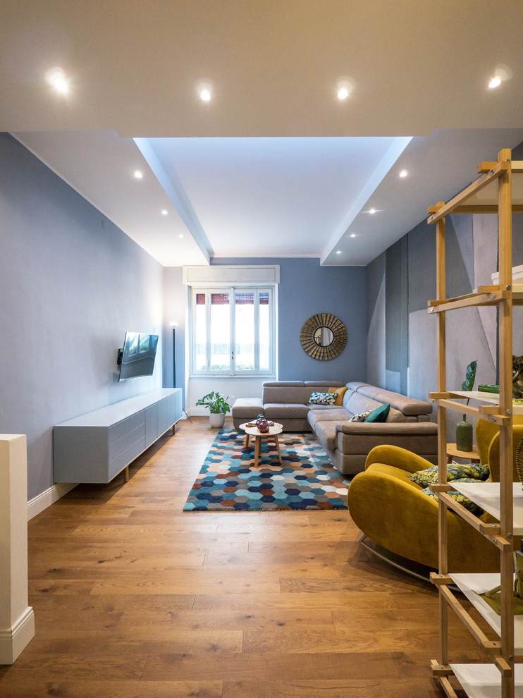 Foto di un soggiorno minimal con pareti blu, pavimento in legno massello medio, TV a parete e pavimento marrone