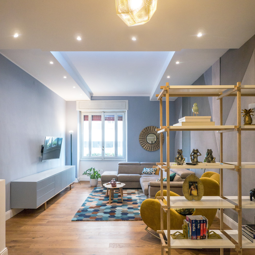 Imagen de salón contemporáneo con paredes azules, suelo de madera en tonos medios, televisor colgado en la pared y suelo marrón