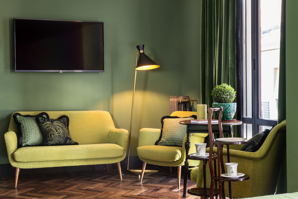 Diseño de sala de estar bohemia con paredes verdes, suelo de madera oscura y televisor colgado en la pared