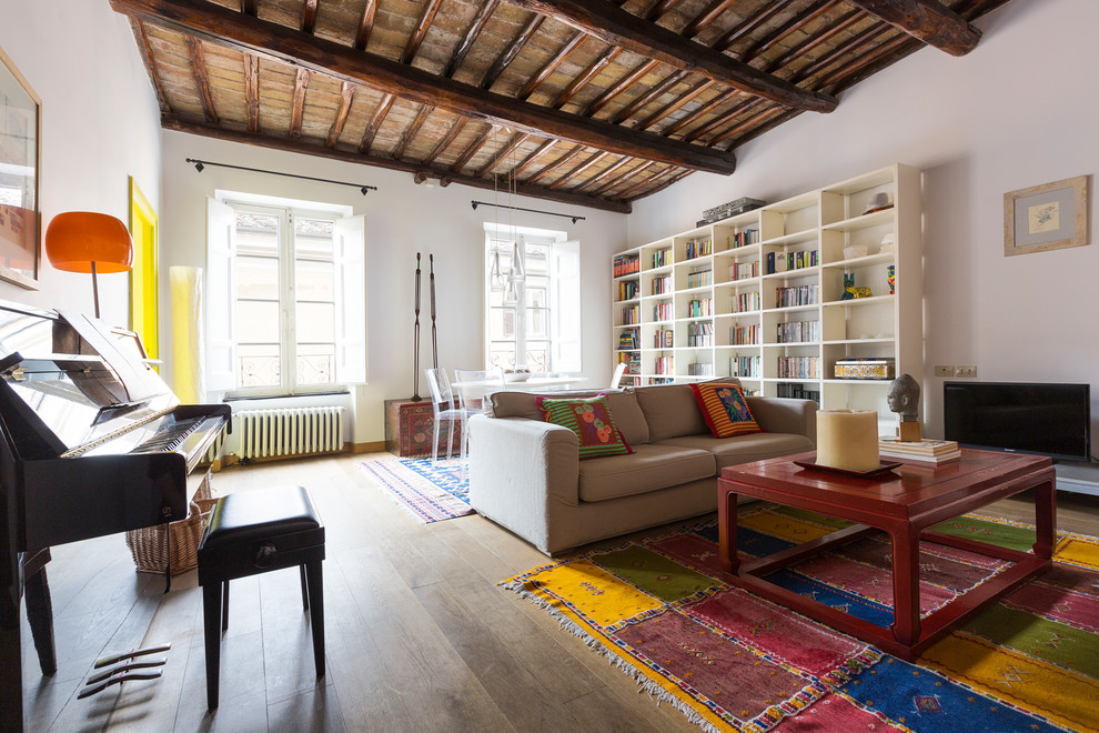 This is an example of an eclectic open plan games room in Rome with a music area, white walls and medium hardwood flooring.