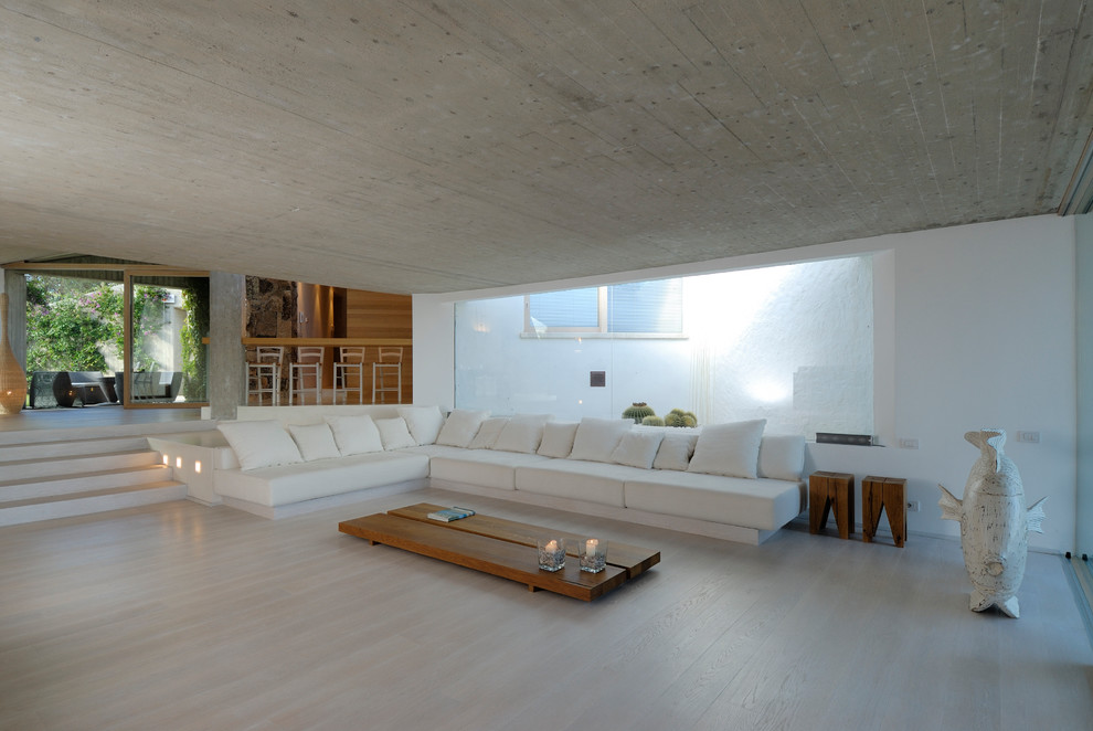 Foto de salón abierto contemporáneo grande con paredes blancas, suelo de madera clara y suelo beige