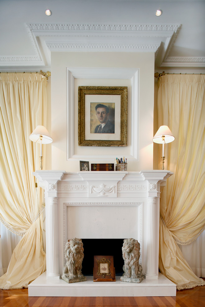 Diseño de salón clásico con paredes beige, suelo de madera en tonos medios, todas las chimeneas, marco de chimenea de yeso y cortinas