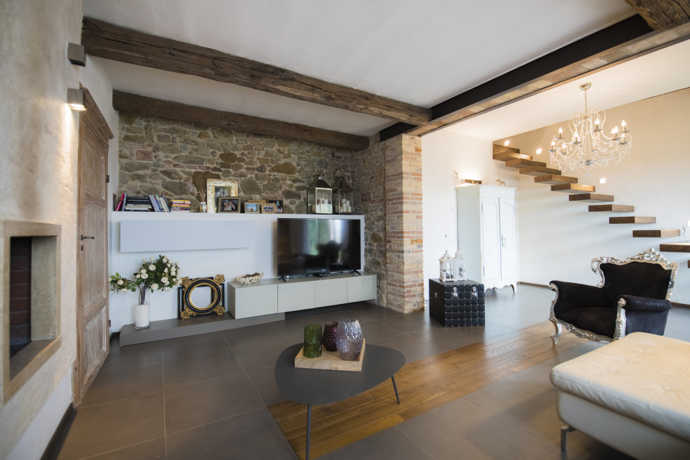 Imagen de salón abierto bohemio de tamaño medio con paredes blancas, televisor independiente, suelo gris y ladrillo