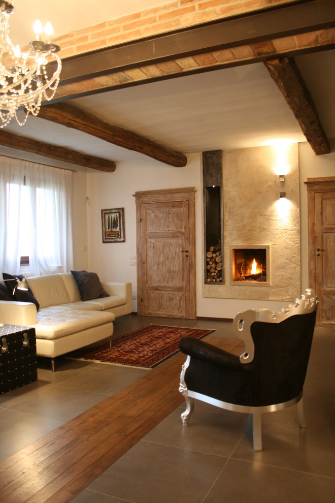 Cette image montre un salon rustique de taille moyenne et ouvert avec un mur beige, un sol en carrelage de porcelaine, une cheminée standard, un manteau de cheminée en plâtre et un sol gris.
