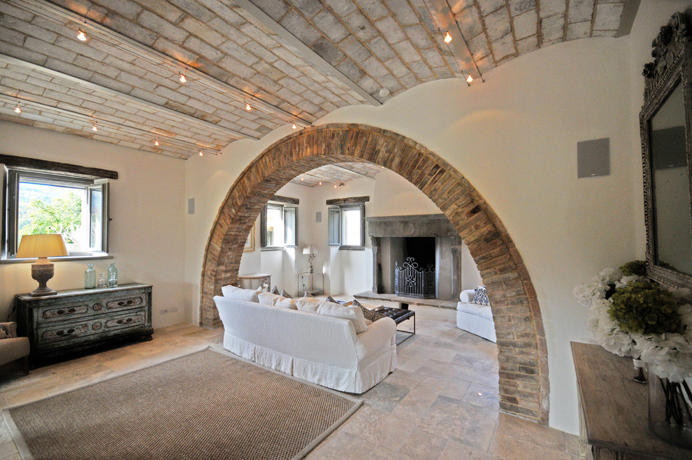 Aménagement d'un très grand salon montagne ouvert avec un mur blanc, un sol en calcaire, une cheminée standard, un manteau de cheminée en pierre et un sol beige.