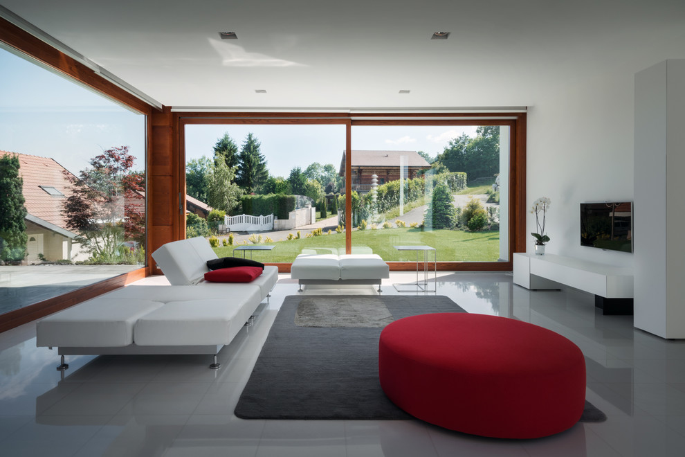 Idee per un soggiorno moderno aperto con pareti bianche, nessun camino, TV a parete, pavimento grigio e tappeto