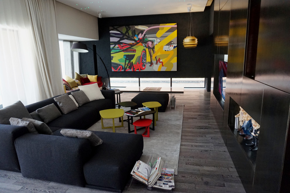 Photo of an expansive industrial open plan living room in Other with a reading nook, multi-coloured walls, dark hardwood flooring, a metal fireplace surround, a wall mounted tv and multi-coloured floors.