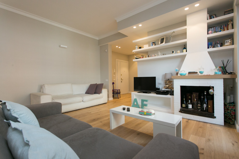 Mittelgroßes, Offenes Modernes Wohnzimmer mit grauer Wandfarbe, hellem Holzboden, Kamin, Kaminumrandung aus Backstein und freistehendem TV in Rom