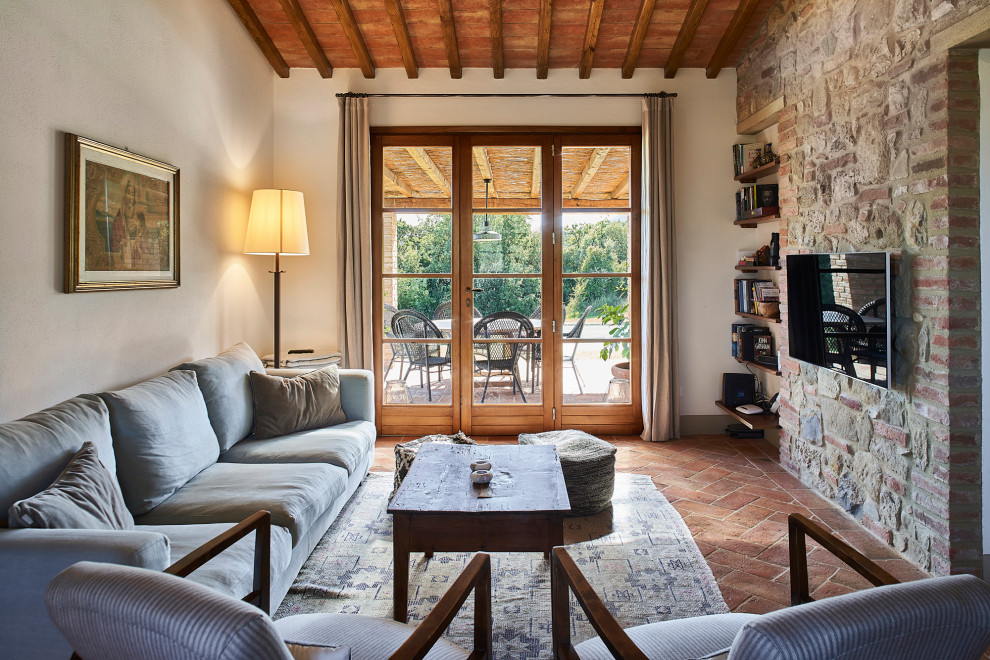 Mittelgroßes Landhausstil Wohnzimmer mit beiger Wandfarbe, Terrakottaboden, TV-Wand, braunem Boden und Ziegelwänden in Florenz