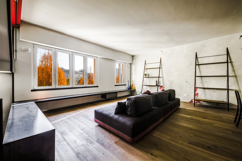 Modelo de salón abierto urbano de tamaño medio sin chimenea con paredes grises y suelo de madera clara