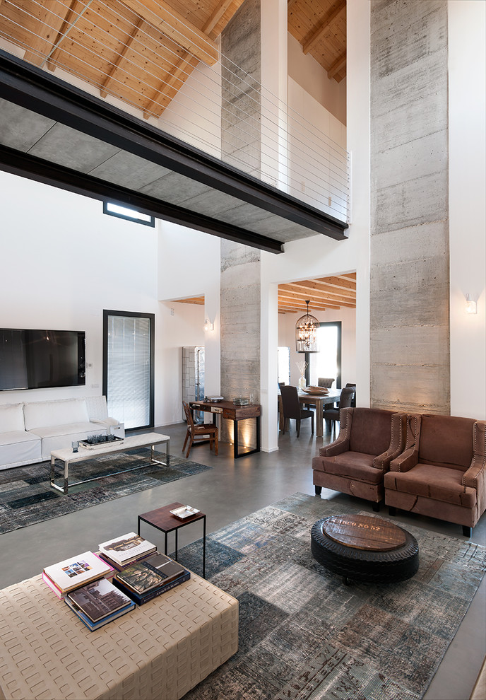 Источник вдохновения для домашнего уюта: открытая гостиная комната в современном стиле с белыми стенами, бетонным полом, телевизором на стене и ковром на полу