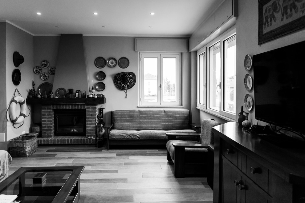 ミラノにあるラグジュアリーな中くらいなラスティックスタイルのおしゃれなLDK (グレーの壁、大理石の床、標準型暖炉、レンガの暖炉まわり、茶色い床) の写真
