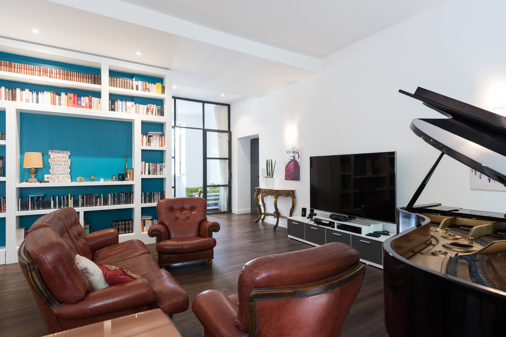 На фото: большая открытая гостиная комната в стиле фьюжн с с книжными шкафами и полками, белыми стенами, темным паркетным полом и отдельно стоящим телевизором