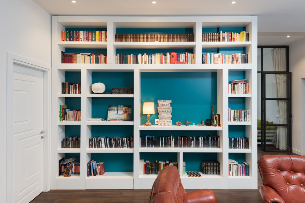 Immagine di un grande soggiorno minimalista aperto con libreria, pareti bianche e parquet scuro