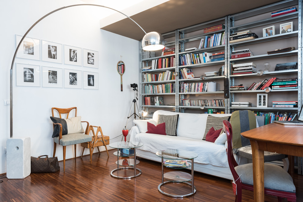 Foto på ett eklektiskt vardagsrum, med ett bibliotek och mellanmörkt trägolv