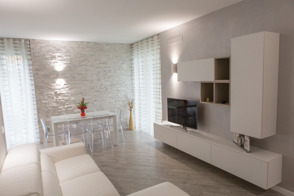 Idee per un soggiorno minimalista di medie dimensioni e aperto con pareti grigie, pavimento in gres porcellanato, TV a parete e pavimento grigio
