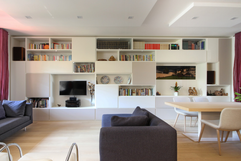 Diseño de biblioteca en casa abierta moderna grande con paredes blancas, suelo de madera en tonos medios, televisor colgado en la pared y suelo amarillo