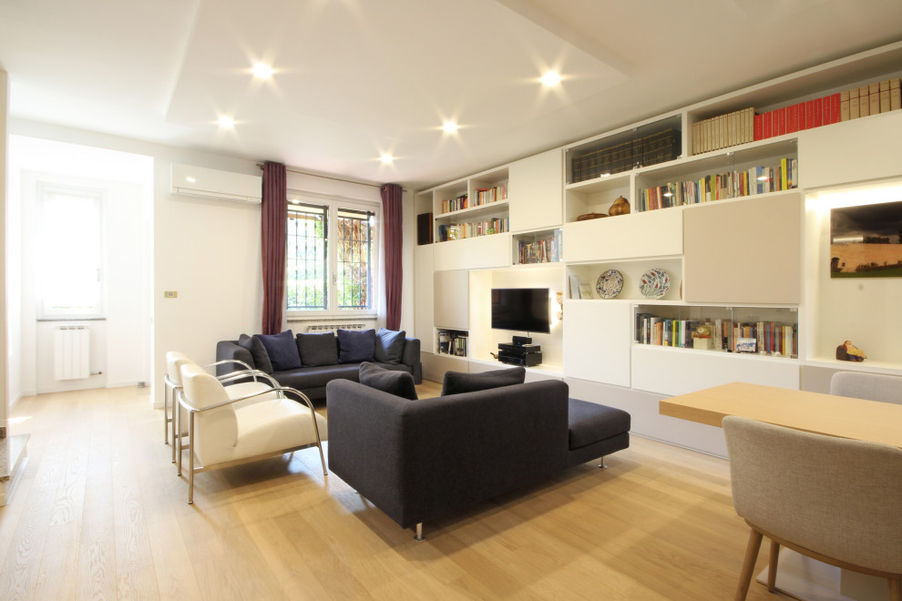 Foto de biblioteca en casa abierta moderna grande con paredes blancas, suelo de madera en tonos medios, televisor colgado en la pared y suelo amarillo