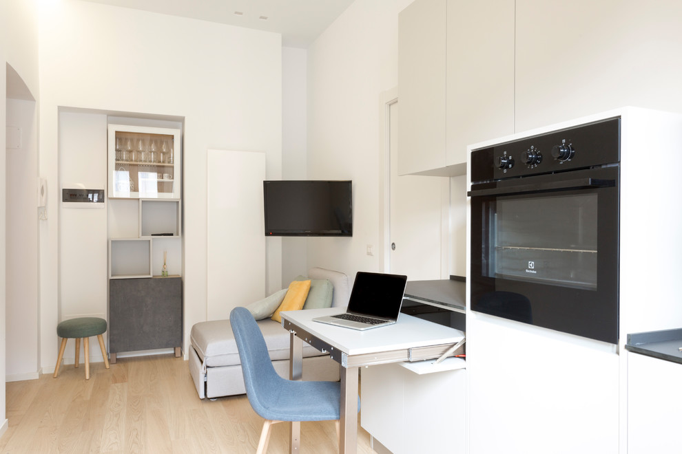 На фото: маленькая изолированная гостиная комната в современном стиле с белыми стенами, светлым паркетным полом и телевизором на стене без камина для на участке и в саду с