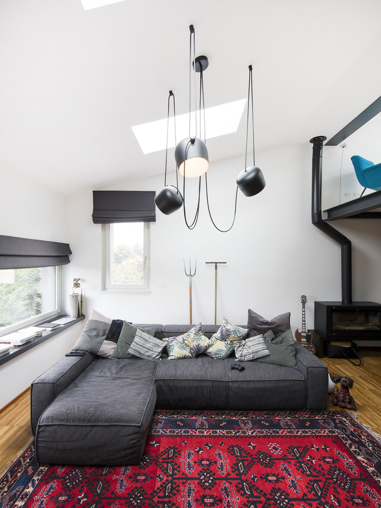 Modernes Wohnzimmer mit weißer Wandfarbe, braunem Holzboden, Kaminofen und braunem Boden in Turin