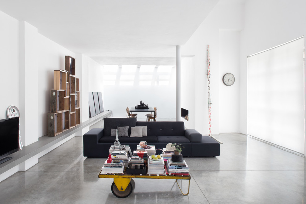 Cette image montre un grand salon design ouvert avec un mur blanc et sol en béton ciré.